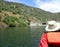 Kayaker in orange vest with hat in kayak on river with hills