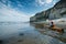 kayaker paddling around serene beach cove, cliffs in distance