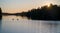 Kayakers and boaters on the lake water along the thickly growing forest vegetation at sunset