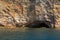 Kayakers passing a sea cave set into a sheer cliff