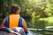 Kayaking and canoeing. Young woman in boat with oars swims on wild river in jungle. Tourist girl in canoe with oar