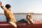 Kayaking with dogs: man stretches sitting in a row boat on the lake next to his spaniel.