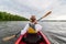 Kayaking travel. Young lady paddling the red kayak. Back view. Holiday and summer adventure