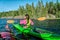 Kayaking women holding paddles horizontally while passing close another kayaking person. She wears magenta jacket and green safety