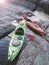 Kayaks stand moored on a rocky seashore.