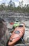 Kayaks stand moored on a stony seashore, in the background of a