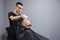 Kazakh barber shaves beard with a razor to a client in a barbershop, a young guy is doing a beard haircut against a gray wall,