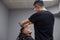 Kazakh barber shaves beard with a razor to a client in a barbershop, a young guy is doing a beard haircut against a gray wall,