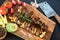 Kebabs - grilled meat and vegetables. Pork skewers on wooden cutting board. Fresh tasty barbecue on black background. Summer