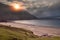 Keem bay and beach at sunrise. Dramatic dark cloudy sky low over ocean and mountain. Sun rising over a ridge. Calm and moody