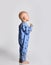 Keen barefooted baby boy in blue fleece jumpsuit with stars stands side to camera looking at upper corner with interest