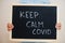 Keep calm covid. Coronavirus concept. Boy hold inscription on the board