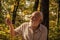 Keep cheerfulness. Pensioner hiking in forest on sunny autumn day. Happy man enjoy autumn nature. Bearded grandfather