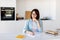 Keep diary, write down thoughts and ideas. Dreamy young lady sitting in kitchen and writing in notebook with pen