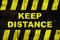 Keep distance text as warning sign with yellow and black stripes on painted wooden wall