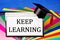 Keep learning-lettering reminder on rainbow sheets of paper for school creativity and the student`s graduation cap. Opportunity t