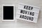 `Keep moving around` words on modern board, tablet on a white wooden surface, top view. From above, flat lay, overhead