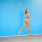 Keep it moving. Portrait of an attractive young woman running against a blue brick wall.