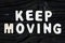 Keep Moving words on dark wooden background