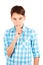 Keep my secret! Serious teen boy in plaid shirt holding finger on lips and looking at camera isolated on white background