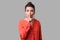 Keep silence! Portrait of elegant woman with bun hairstyle, big earrings and in red blouse. indoor studio shot isolated on gray