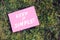 Keep it simple quote written on pink paper on green grass background. Peaceful, comfortable and simplified life concept