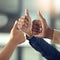 Keep up the exceptional work. Closeup shot of a group of businesspeople giving thumbs up together.