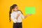 Keep your eye out for the idea. Happy girl pointing finger at certain idea on yellow background. Small cute kid smiling