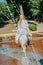 Keeping cool in the heat. Young woman in water spray in city park fountain. What to wear on a hot day