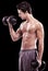 Keeping well-toned. Side view of a bare-chested young man lifting dumbbells isolated on black.