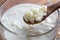 Kefir grains on a wooden spoon above a jar of milk kefir