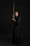 Kendo guru wearing in a traditional japanese kimono is practicing martial art with the shinai bamboo sword against a