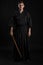 Kendo guru wearing in a traditional japanese kimono is practicing martial art with the shinai bamboo sword against a