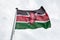 Kenya flag on a pole waving, cloudy sky background