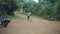 KENYA, KISUMU - MAY 20, 2017: Back view of boy walking through the road in Africa. Male with bicycle walking in forest.