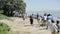 KENYA, KISUMU - MAY 20, 2017: Group of african and caucasian people with children walking on the shore of the sea.