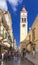 KERKYRA, CORFU, GREECE - SEPTEMPER 26 2018: Bell tower of Saint Spiridon church, many tourists are on narrow ancient streets of