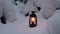 A kerosene lamp burning in a snowy beautiful fairy forest, against the background of trees covered with snow