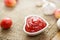 Ketchup in bowl heart shape on sack and wooden background