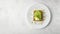 keto bread with avocado, elegantly served on a white plate atop a pristine table against a white wall backdrop