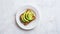 keto bread with avocado, elegantly served on a white plate atop a pristine table against a white wall backdrop