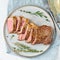 Keto ketogenic diet beef steak, striploin on gray plate on white background. Paleo food recipe with chopped piece of meat and