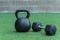 A Kettlebell and a hexagonal dumbbell side by side on synthetic grass