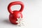 Kettlebell winter fitness, red kettlebell on a white background with silver sparkles and a white snowflake