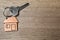 Key with trinket in shape of house on wooden background, top view and space for text. Real estate services