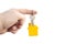 Key with a yellow shaped house on a chain in a hand on a white background.