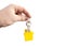 Key with a yellow shaped house on a chain in a hand on a white background