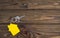 Key with yellow shaped house keychain on chain on wood texture background.