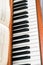 The keyboard of a brown upright piano with blurred sheet music.