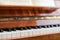 The keyboard of a brown upright piano with sheet music.